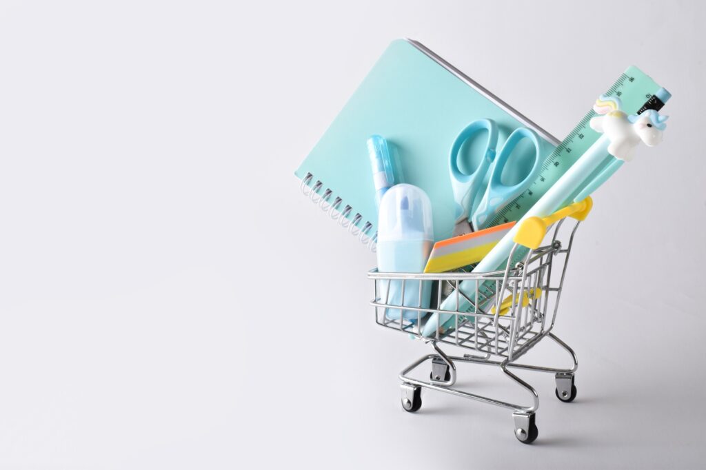 Blue stationery in a mini supermarket cart on a white background