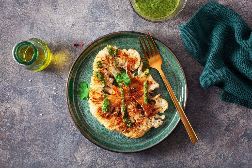 cauliflower steaks with herb sauce and spice. plant based meat substitute