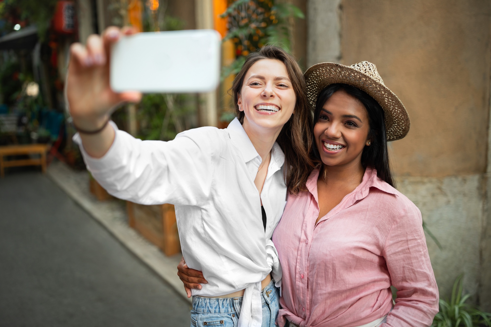 Cheerful young different ladies in casual make selfie on phone enjoy trip in new city, outside