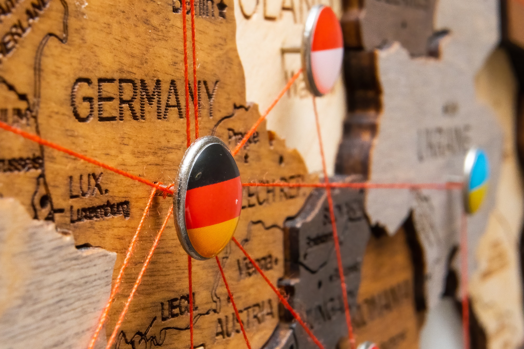 Germany, Poland and Ukraine flags on the pin with red thread showed the paths on the wooden map.