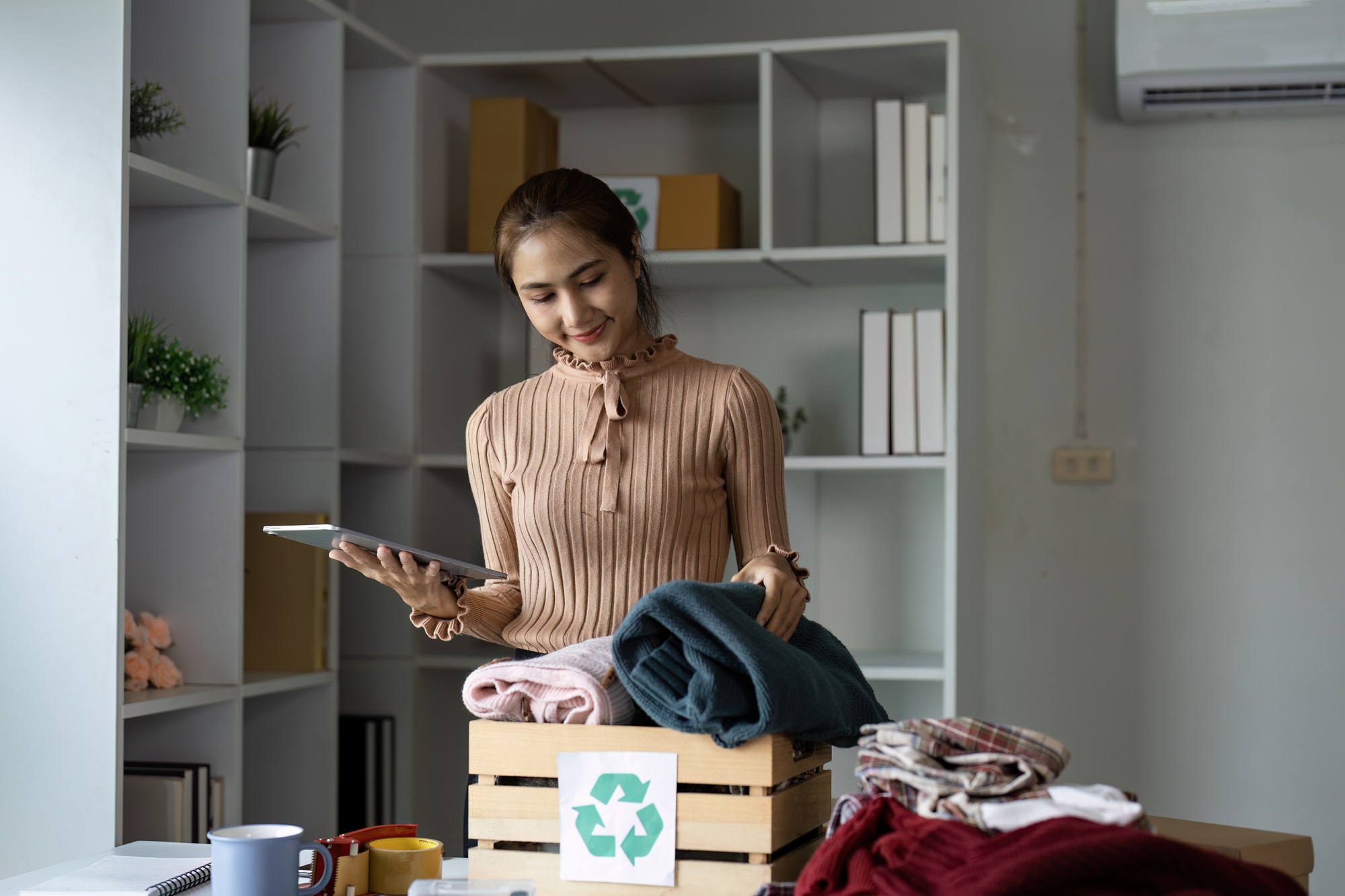 Recycling initiative a woman organizing clothes for sustainable reuse at home in a minimalist space